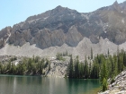 Dave sitting next to Goat Lakes with some colorful cliffs above.