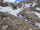 Creek emerging from a snowfield.