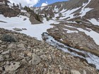 Creek emerging from a snowfield.