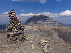 Massive summit cairn on Eiffel Peak, with Mount Temple looming in the background.